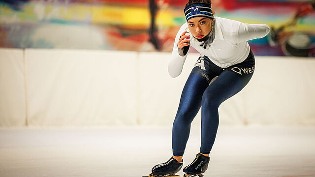 Schaatsster in lage houding op de ringbaan